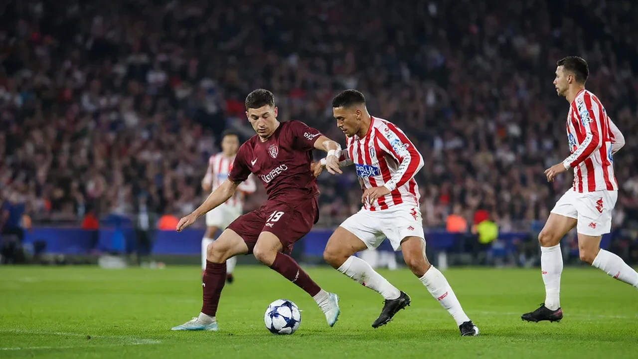 Two players in red and white shirts battling for a loose ball at the edge of the area under floodlights