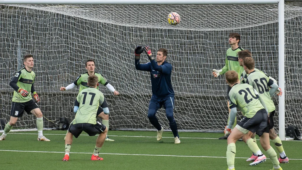Goalkeeper punching the ball clear under pressure from an opposing forward