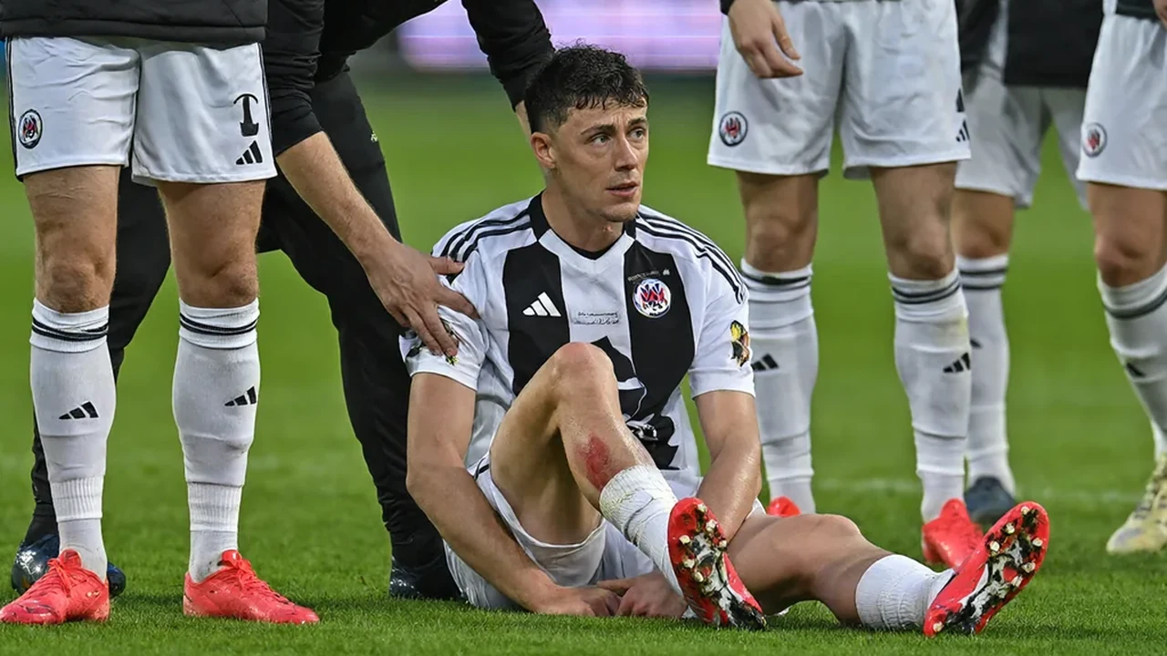 Physio treating a player on the touchline while the crowd looks on