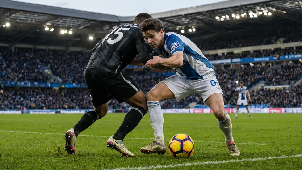 Two players contesting the ball on the touchline in a packed Premier League stadium