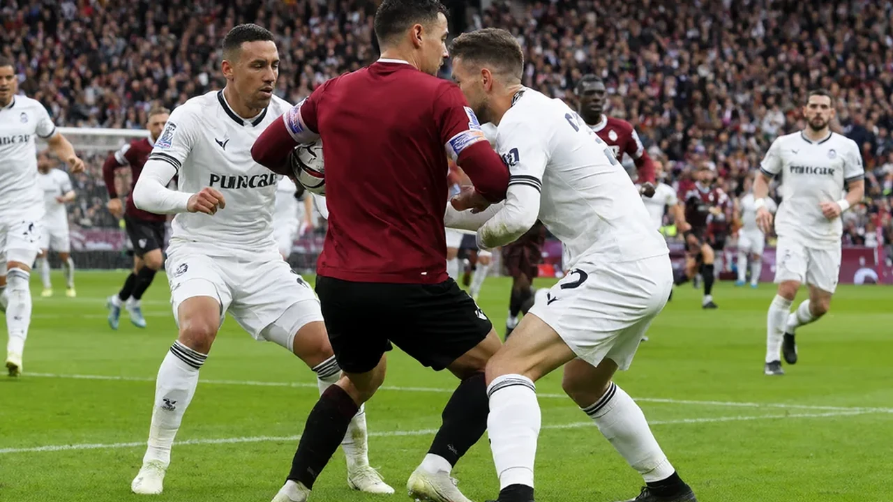 A centre-forward in a red shirt holding the ball up as two defenders close in